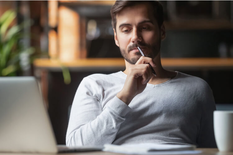 man thinking in front of laptop