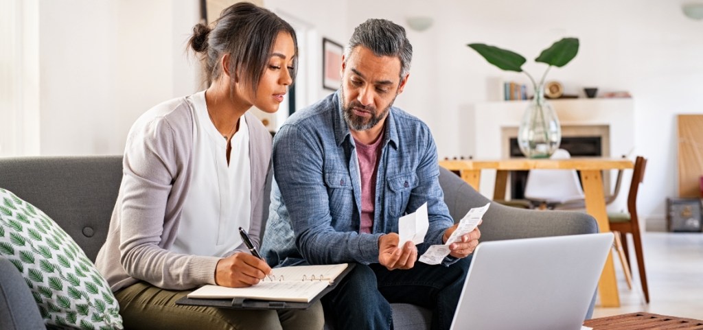 The Battle of Housing Costs: Cities Where Renters & Owners Have it Better couple calculating finances at home using laptop