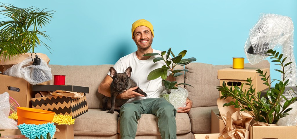 single homeowner hugs pet, rests in own apartment, celebrates move by himself