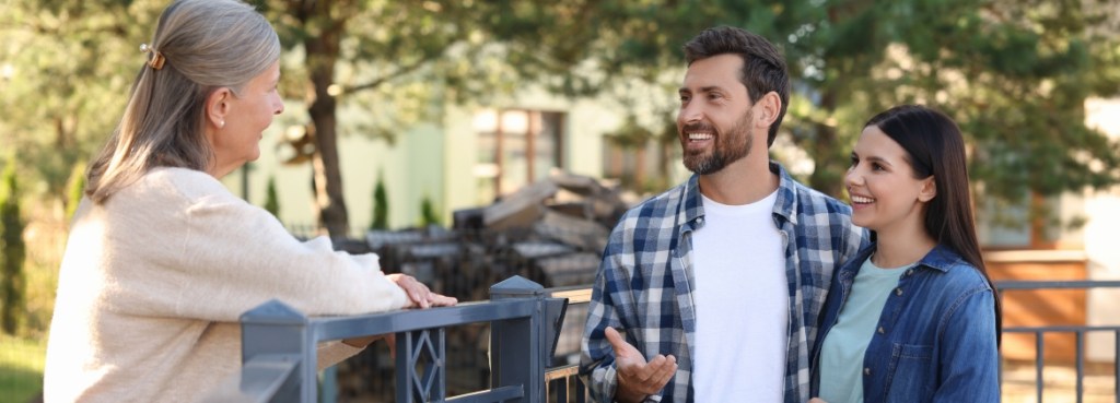 Mastering Neighborly Harmony: A House Renter’s Guide to Preventing Conflicts Friendly relationship with neighbours. Happy young couple of house renters talking to neighbor near shared fence outdoors