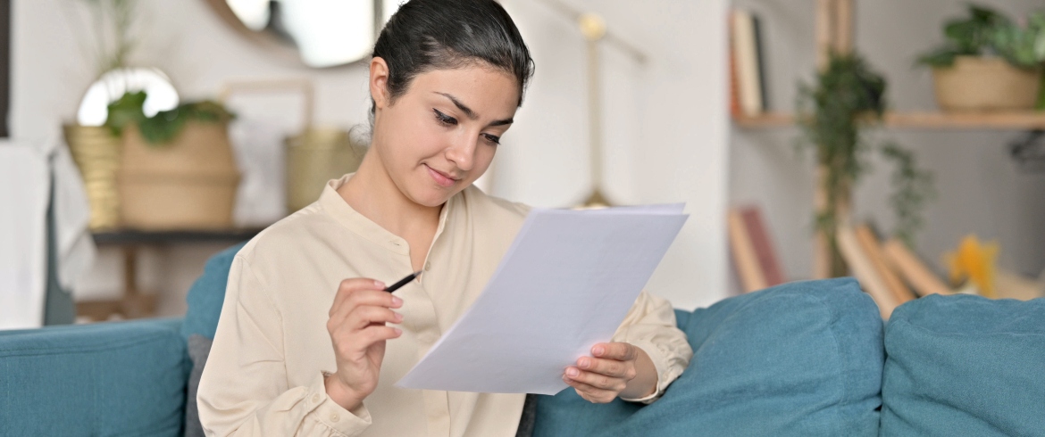 Young Woman Reading a lease on Sofa before signing for a rental