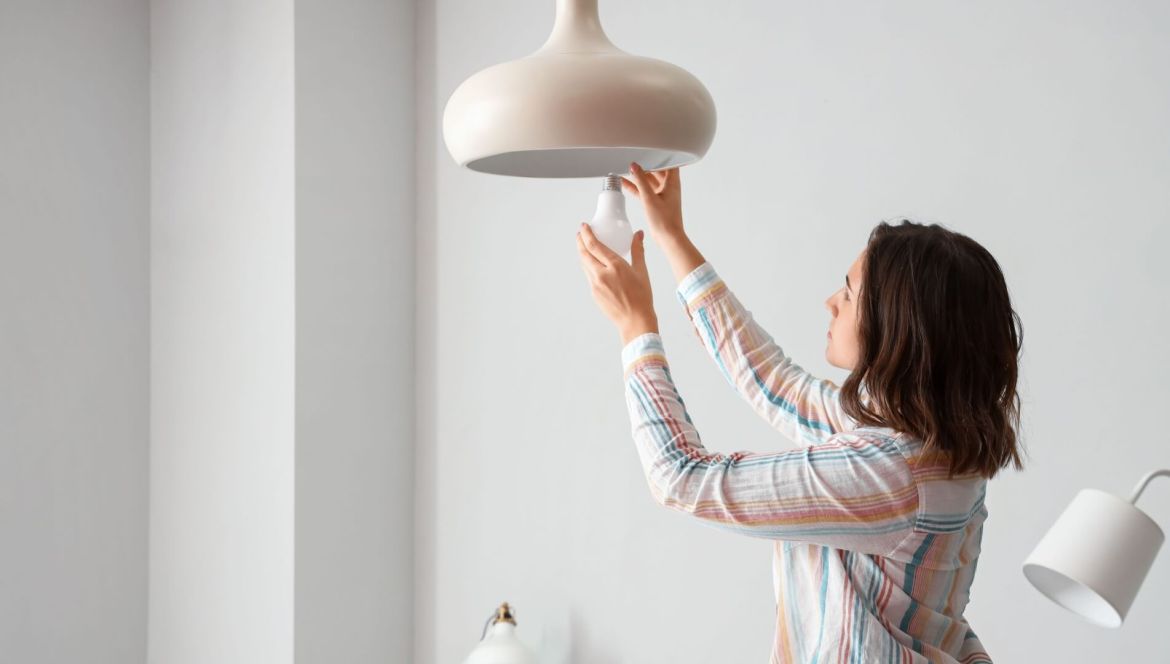 renter changing light bulb in rental house